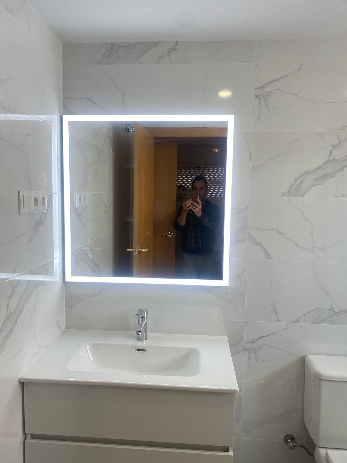 Reforma de baño con modernas luces LED y espejo grande para mejorar la iluminación.