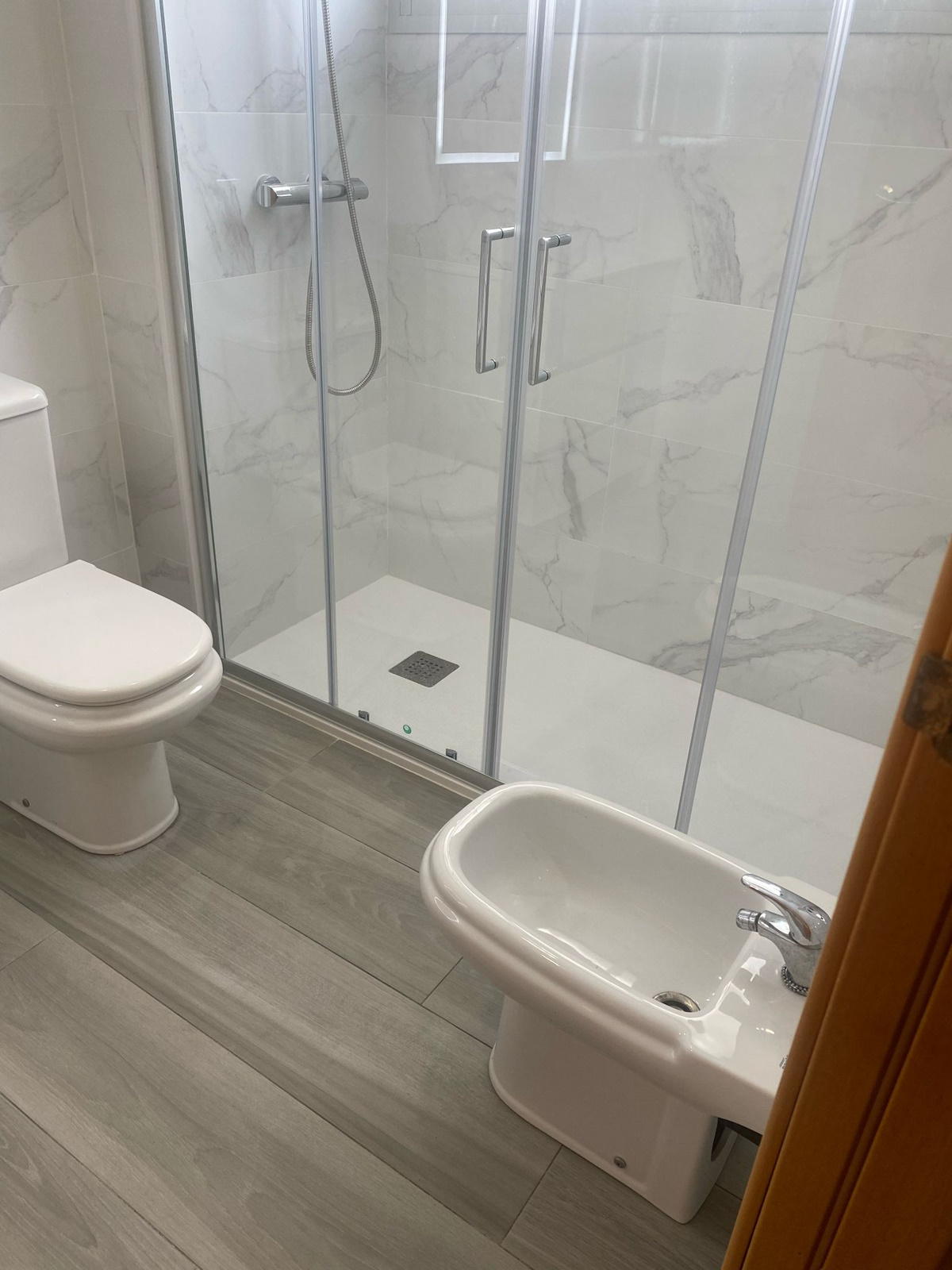 Reforma de baño con revestimientos en tonos neutros y ducha de hidromasaje.