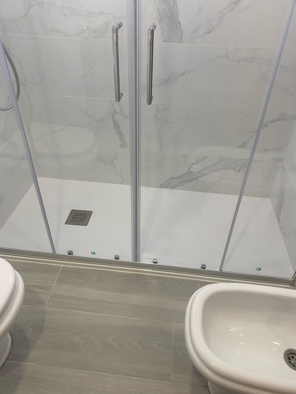 Reforma completa de baño con nuevos azulejos modernos y ducha de esquina.